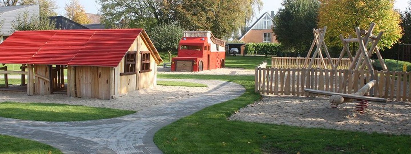 Hof einer Kita mit Holzhäuschen und Klettergerüsten