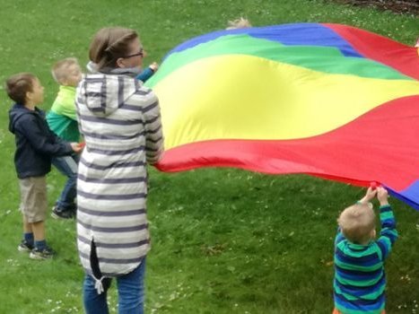Erzieherin spielt mit Kindern und einem bunten Tuch